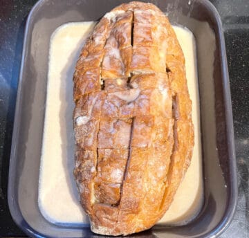 Bread loaf with custard for french toast poured over in baking dish.