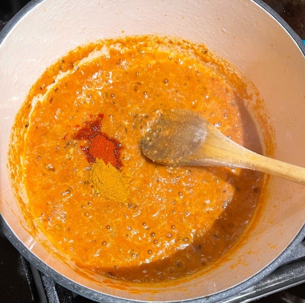 Cayenne and turmeric added to masala paste in pot.