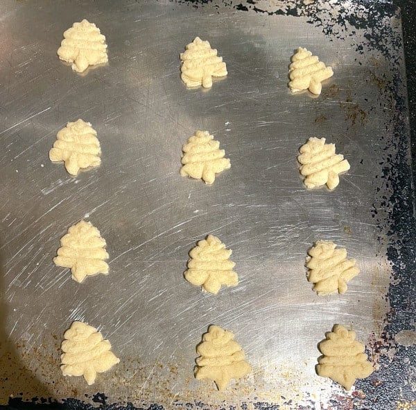 Christmas tree cookies unbaked on a baking sheet.