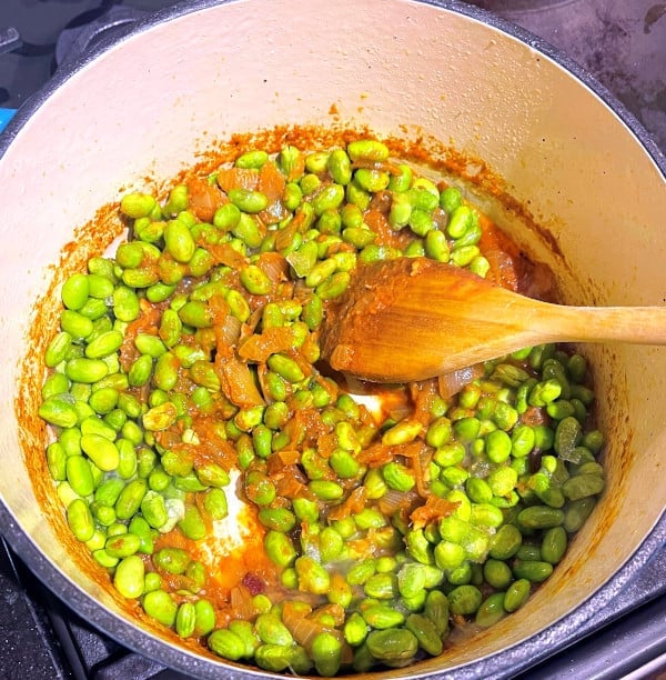 Edamame added to tomatoes and spices in dutch oven.