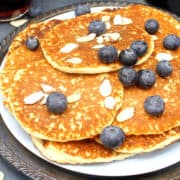 Vegan keto low carb pancakes in plate with blueberries and sliced almonds.