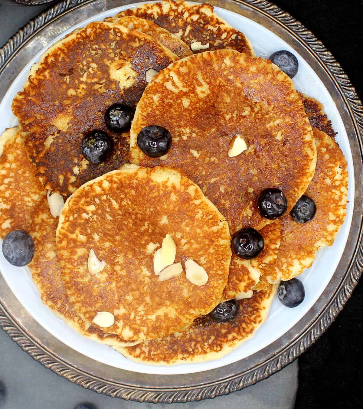 Overhead shot of vegan low-carb keto pancakes with sliced almonds and blueberries in plate.