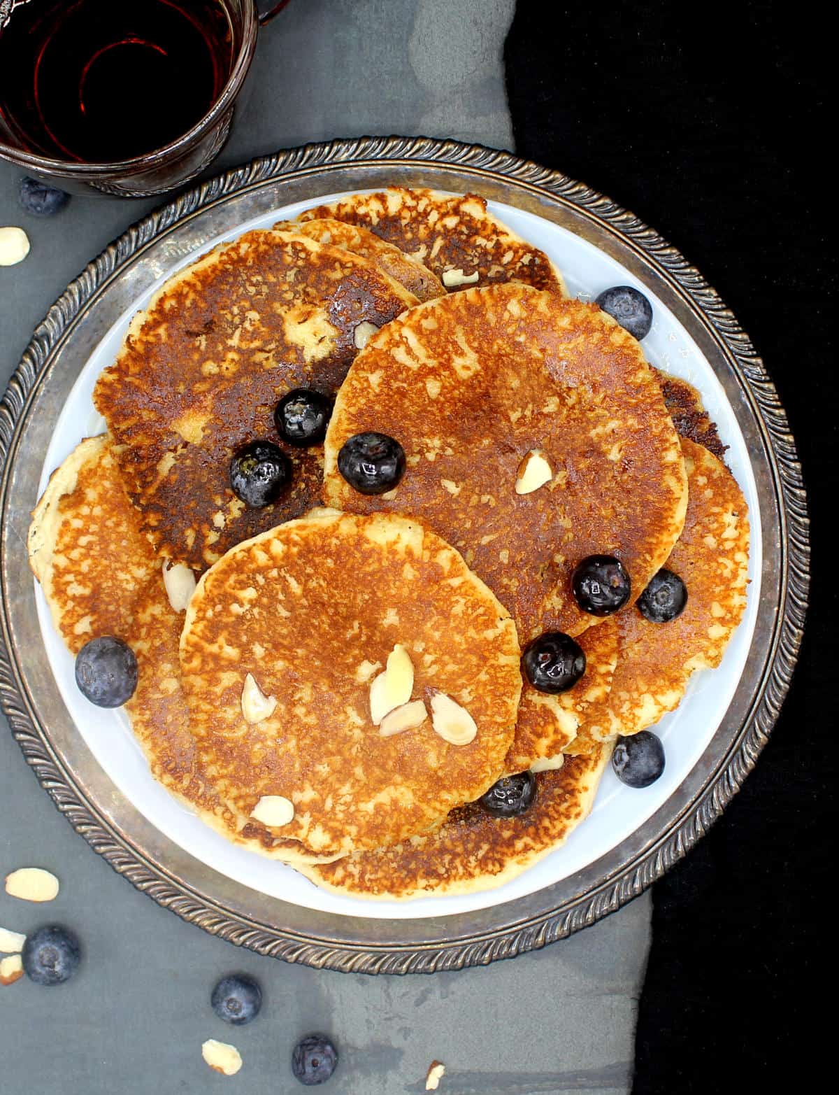 Overhead photo of a stack of vegan keto low carb pancakes in a blue plate with blueberries and sliced almonds.