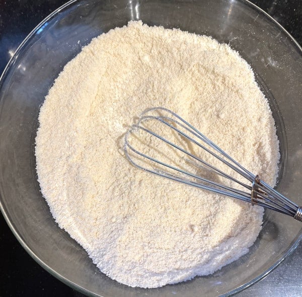 Dry ingredients for keto pancakes in glass bowl with whisk