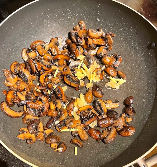 Mushrooms with ginger and garlic added in wok.