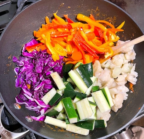 Cabbage, zucchini, bell peppers and cauliflower added to wok.