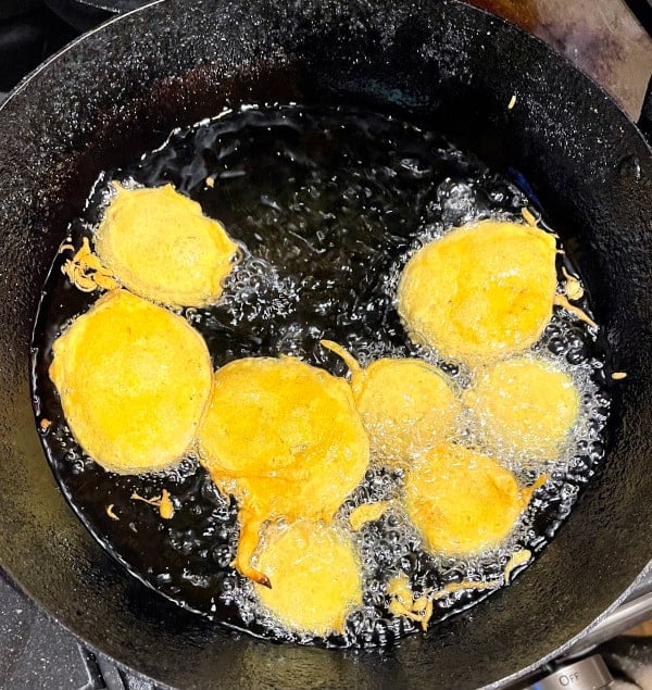 Pakoras frying in oil in a kadhai.