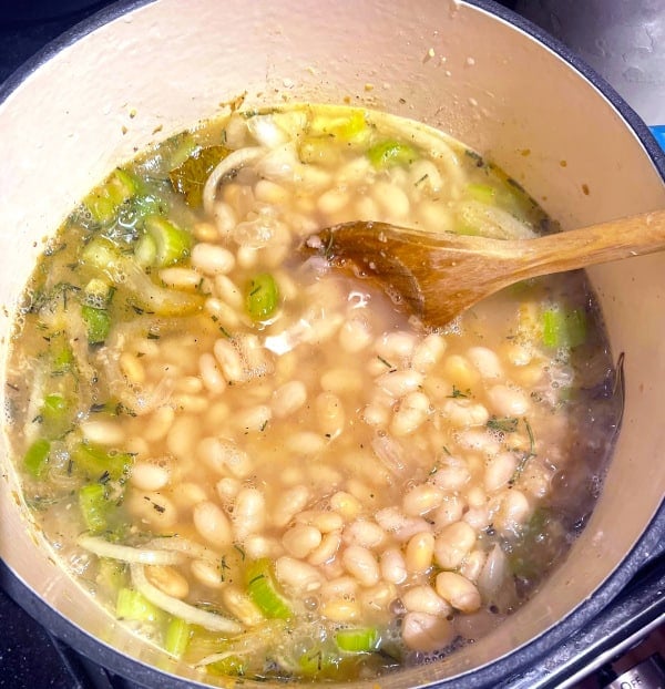 White navy beans added to the soup pot.