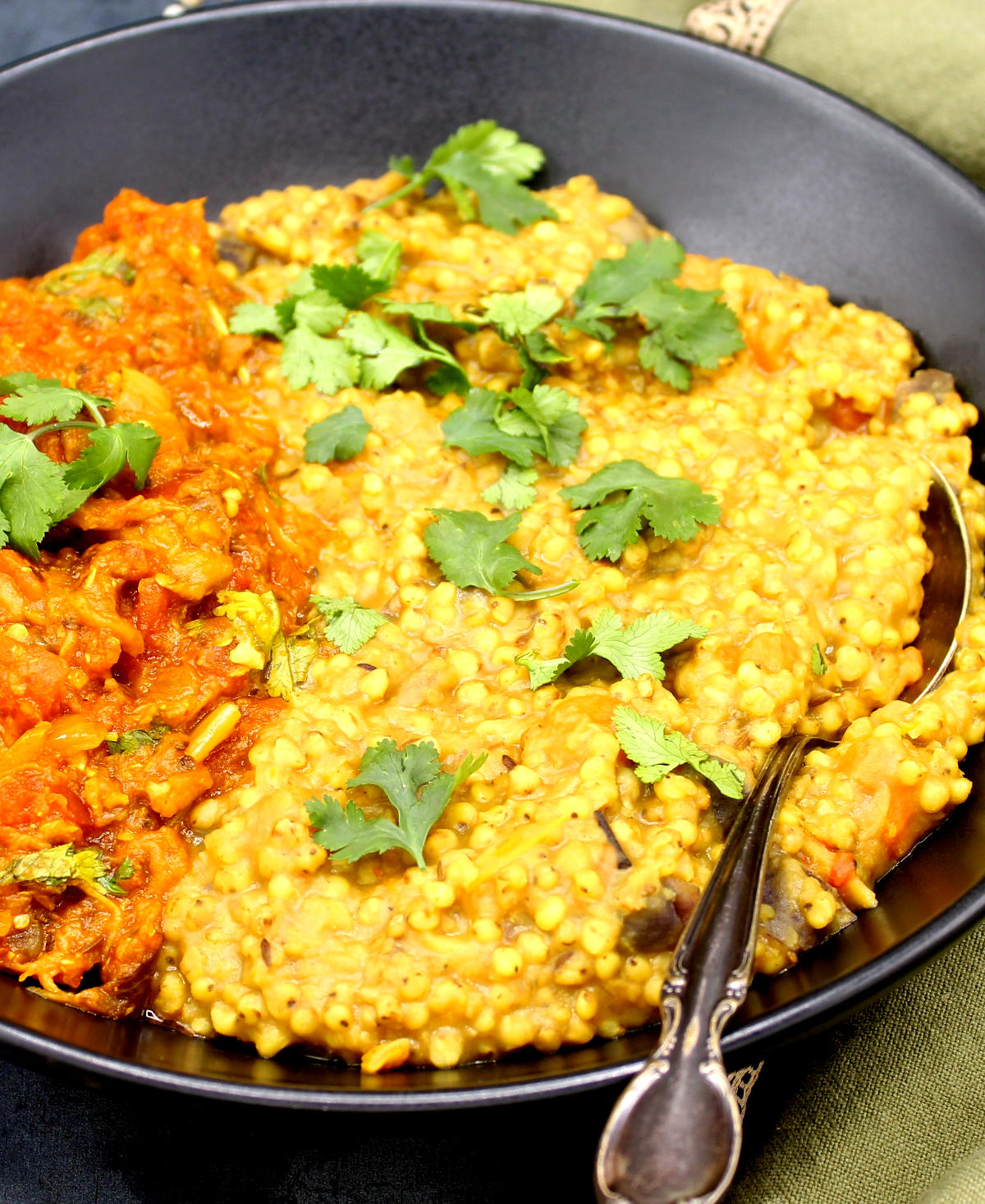 A front closeup of a bowl of jowar khichdi served with eggplant bharta.