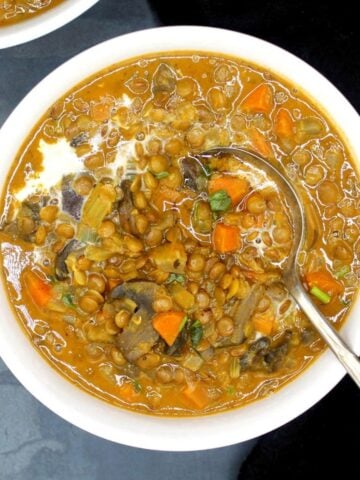 A bowl of lentil soup with veggies and a spoon.