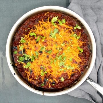 Mexican vegan black bean casserole in a steel skillet with cheese and cilantro.