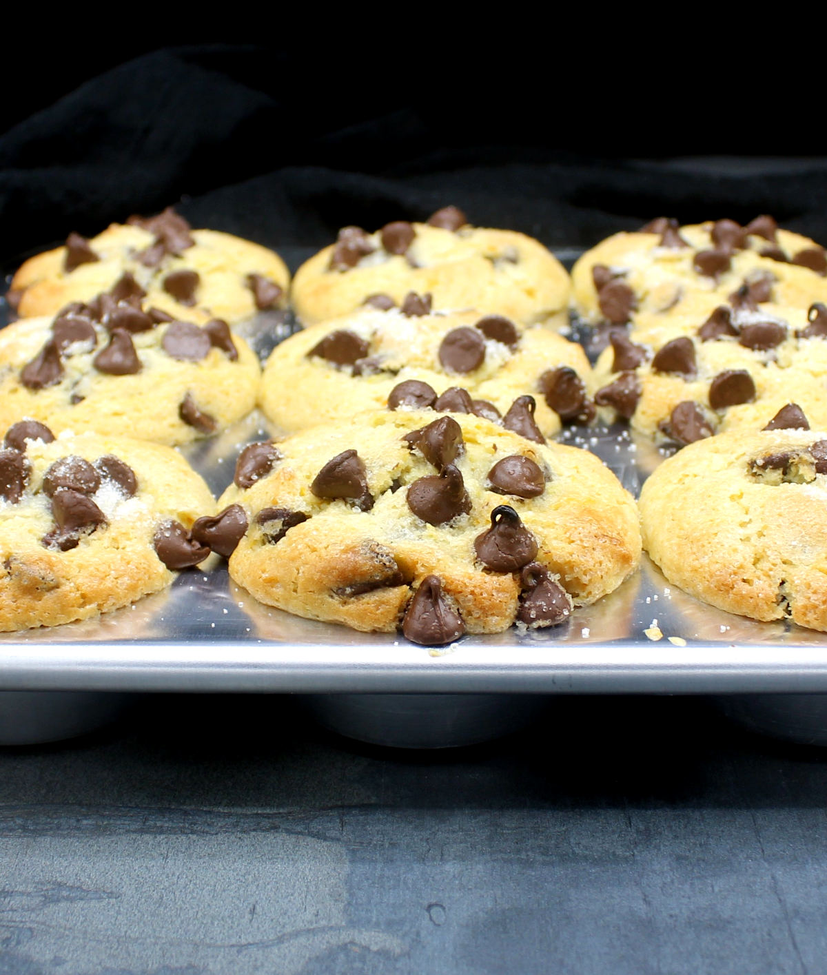 Front closeup of a muffin pan with baked chocolate chip muffins.