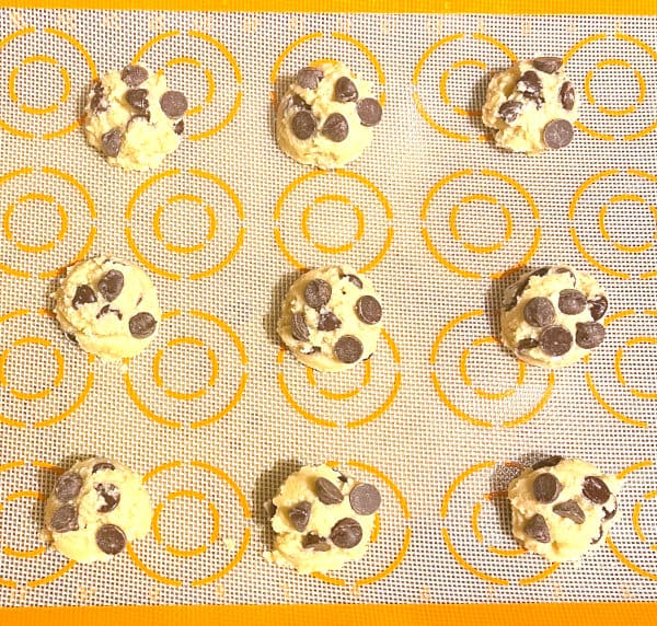 Vegan keto chocolate chip cookie batter rounds on a silpat baking sheet.