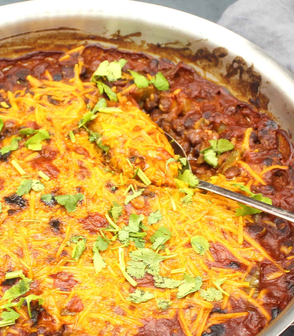 Front closeup of a skillet with black beans and vegan cheddar cheese shreds.