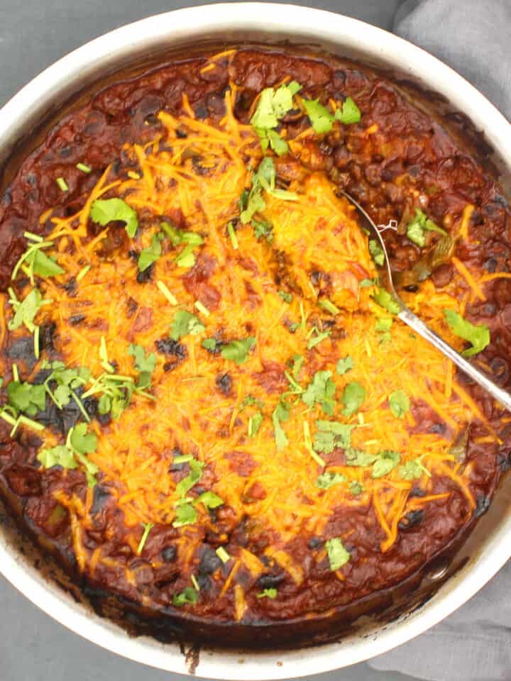 Vegan Mexican black bean casserole in pan with a steel spoon.