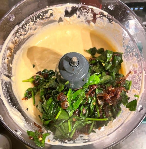 Spinach and caramelized onions added to food processor.