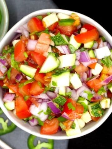Overhead shot of kachumber salad with tomatoes, onions, zucchini, cilantro and jalapenos.