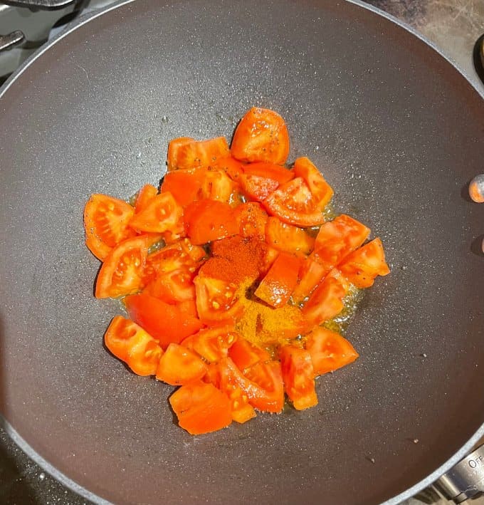 Tomatoes with cayenne and turmeric in saucepan.