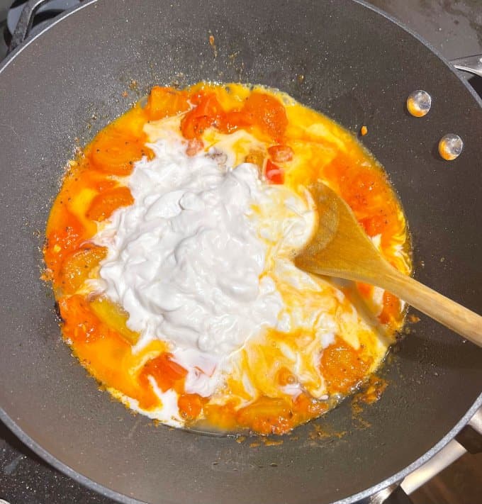 Coconut milk added to tomatoes in saucepan.
