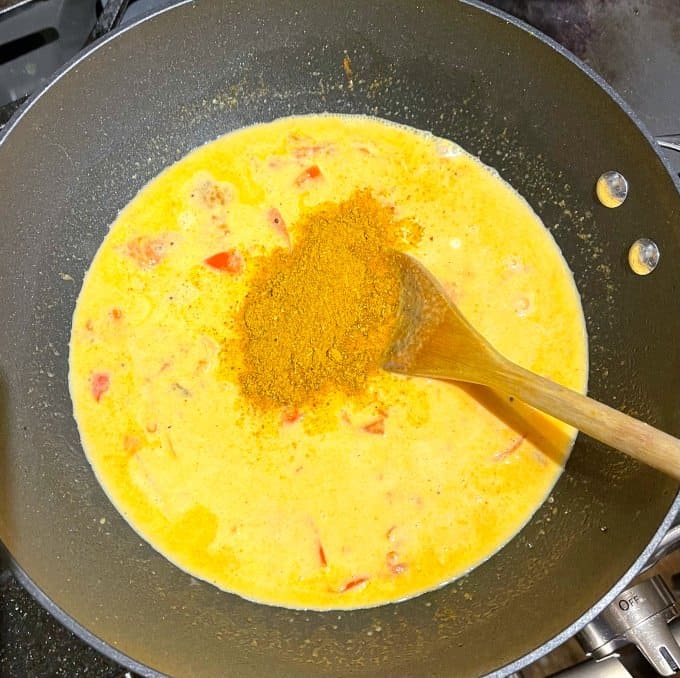 Curry powder added to coconut milk and tomatoes.
