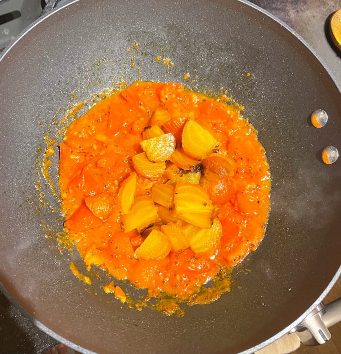 Golden beets added to tomatoes in saucepan.