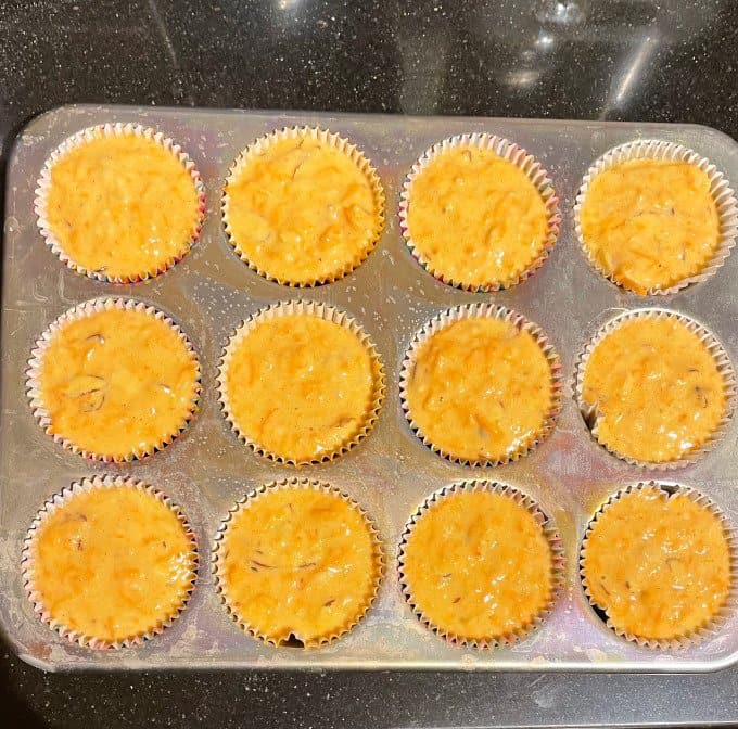 Carrot muffin batter in muffin tins.
