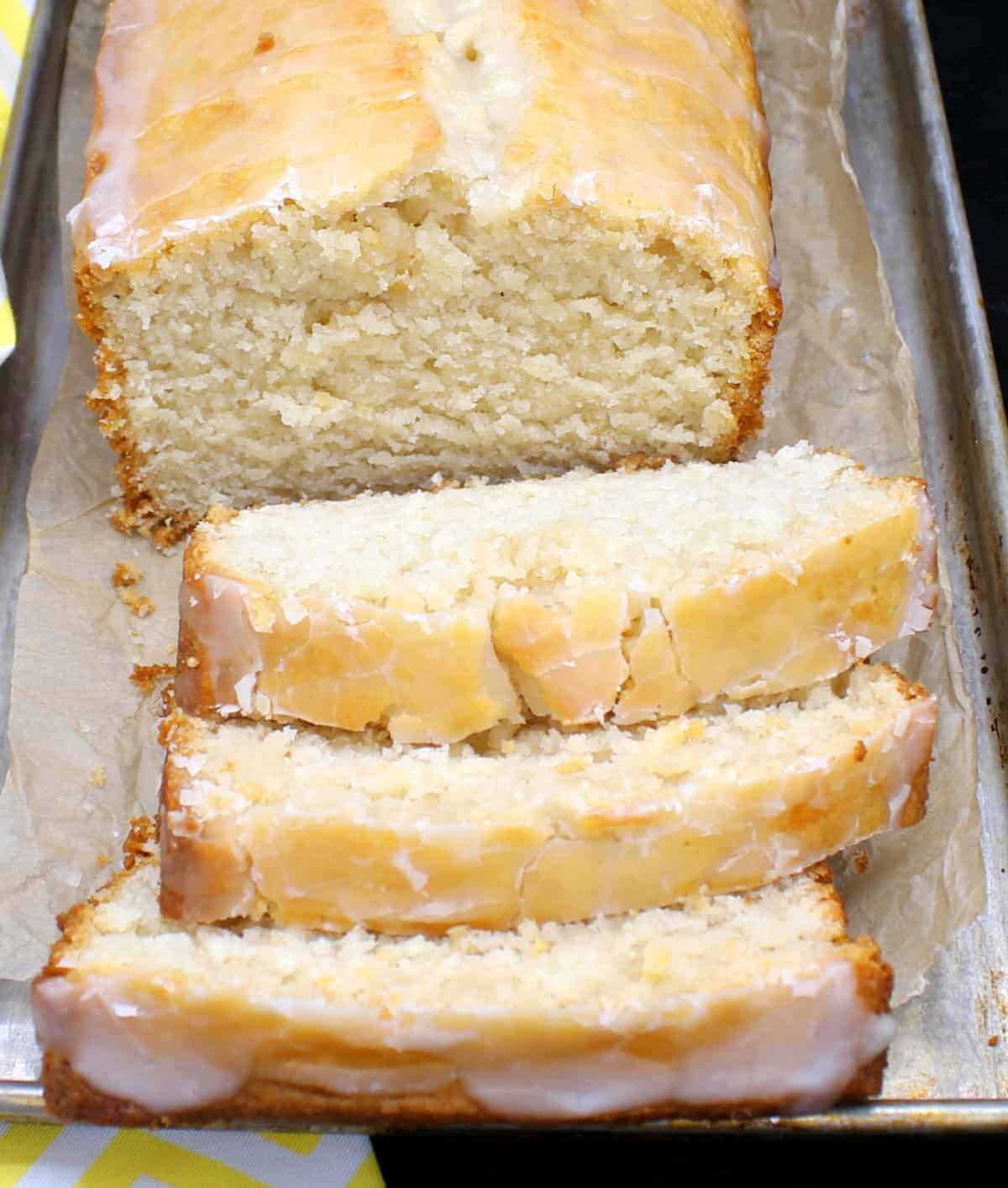 A sliced loaf of vegan lemon pound cake on a baking sheet.