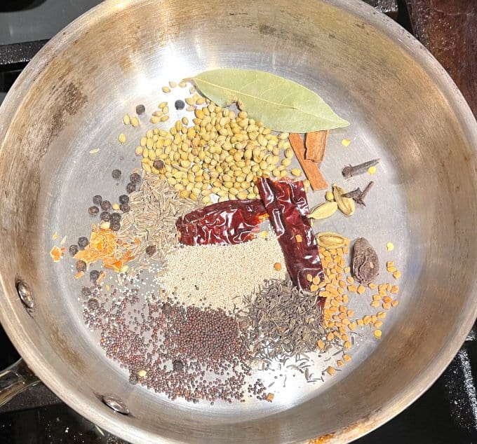 Dhansak masala spice mix ingredients in skillet.