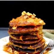 A stack of pancakes on white plate with shredded carrots and walnuts and text inlay that says "carrot cake pancakes, vegan, easy, one-bowl"