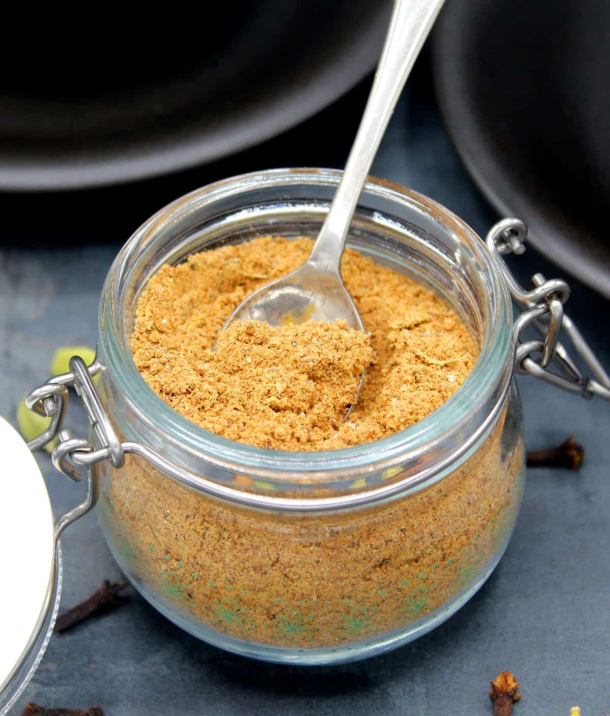 Chai masala in airtight glass container with spoon.