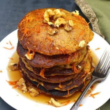 A stack of vegan carrot cake pancakes on a plate with fork.