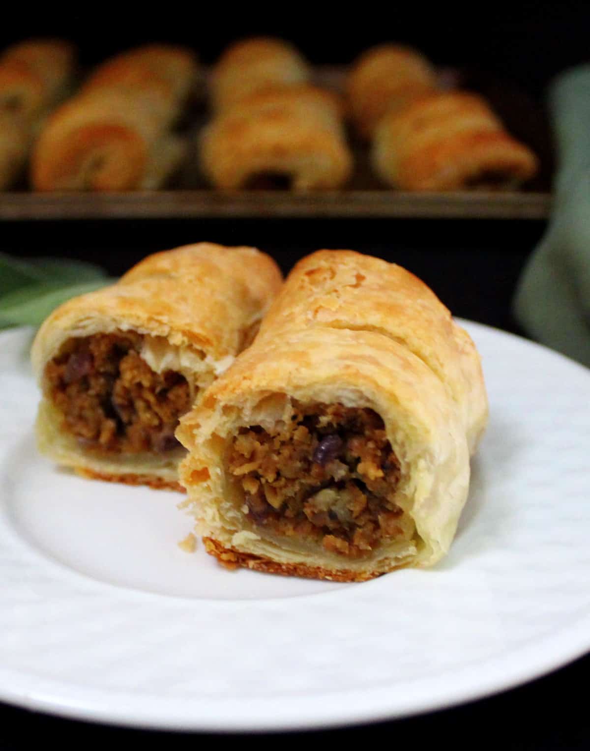 Front photo of vegan sausage rolls with apple sage stuffing on a white plate.