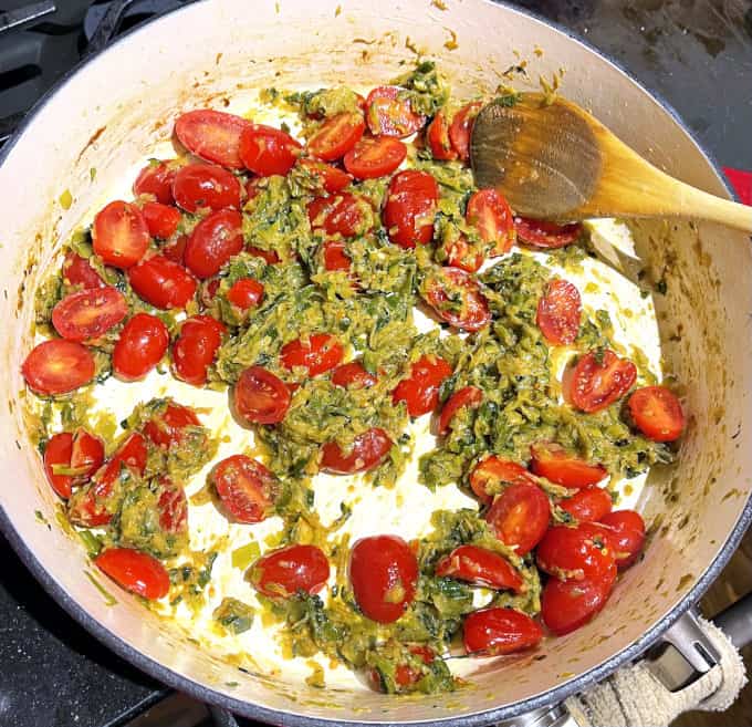 Cherry tomatoes added to leeks and zucchini in skillet.