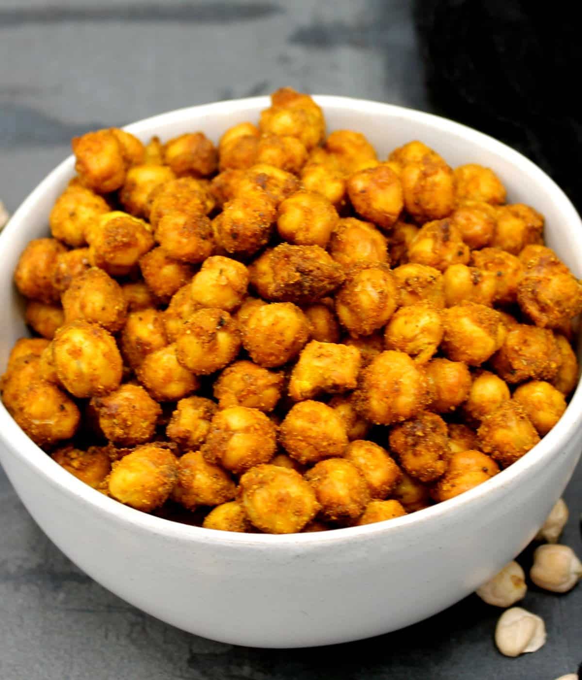 Spicy, tangy air fryer chickpeas in gray bowl with chickpeas scattered around.