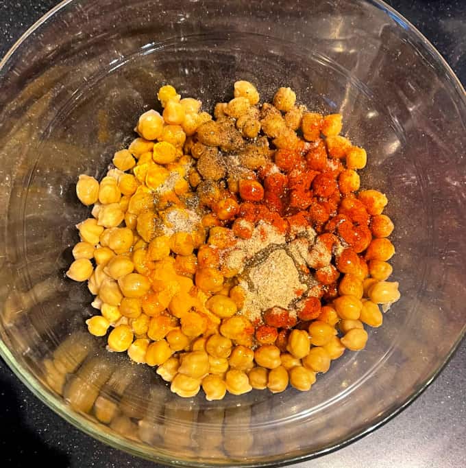 Épices ajoutées aux pois chiches dans un bol.