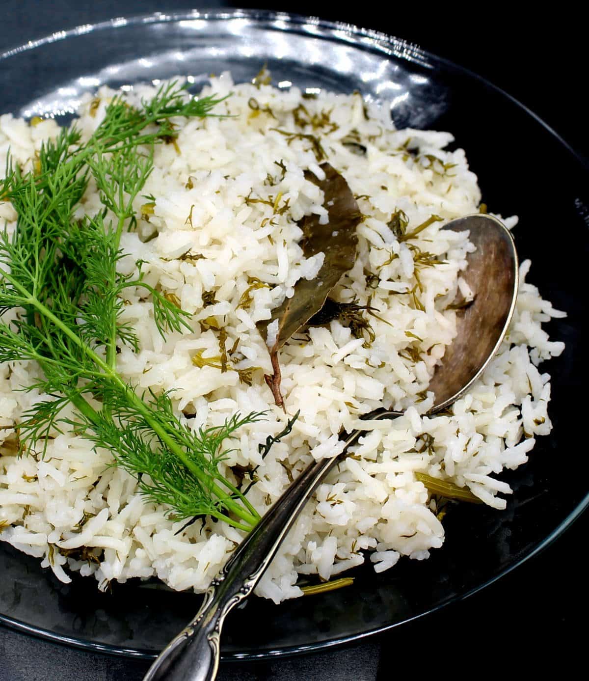 Dill rice in glass bowl with spoon and fresh dill.