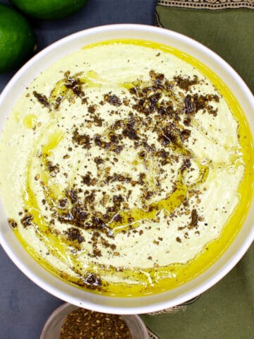 Edamame hummus with za'atar topping in white bowl.