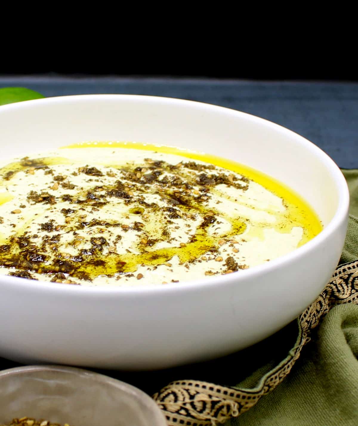 Edamame hummus in white bowl with zaatar and olive oil.