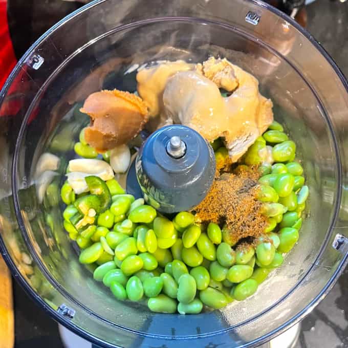 Ingrédients pour le houmous dans le bol du robot culinaire.