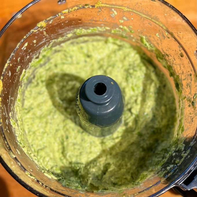 Pesto de ajo verde después de procesarlo en el cuenco del procesador de alimentos.