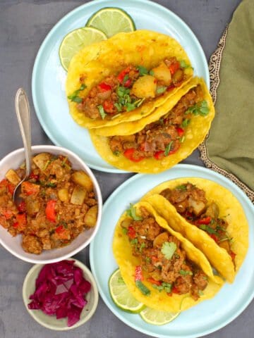 Vegan picadillo tacos in blue plates with bowls of the tacos and beets on the side.