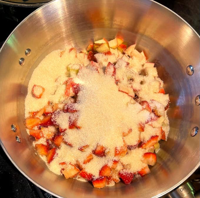 Sugar and other ingredients added to strawberries and rhubarb in pan.