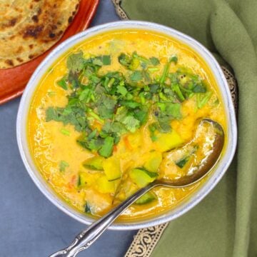 Bowl of vegan zucchini dal with spoon.