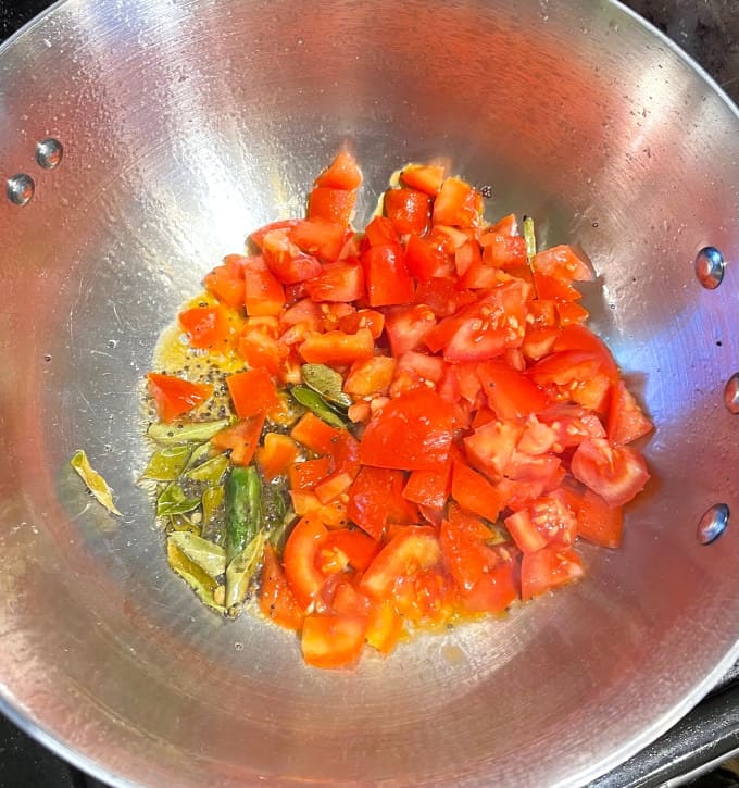 Tomatoes added to tempering in saucepan.