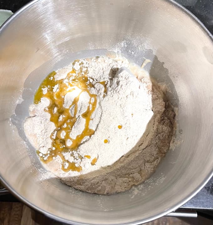 Dry ingredients and olive oil added to yeast in mixing bowl.