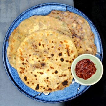 Mixed veg parathas in a plate with Indian pickles.