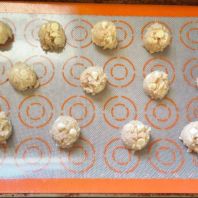 Cookie dough balls scooped out on silpat sheet in baking sheet.