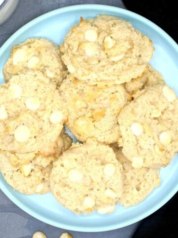 Plate of cookies with text inlay that says "vegan white chocolate macadamia nut cookies, four net carbs per cookie"