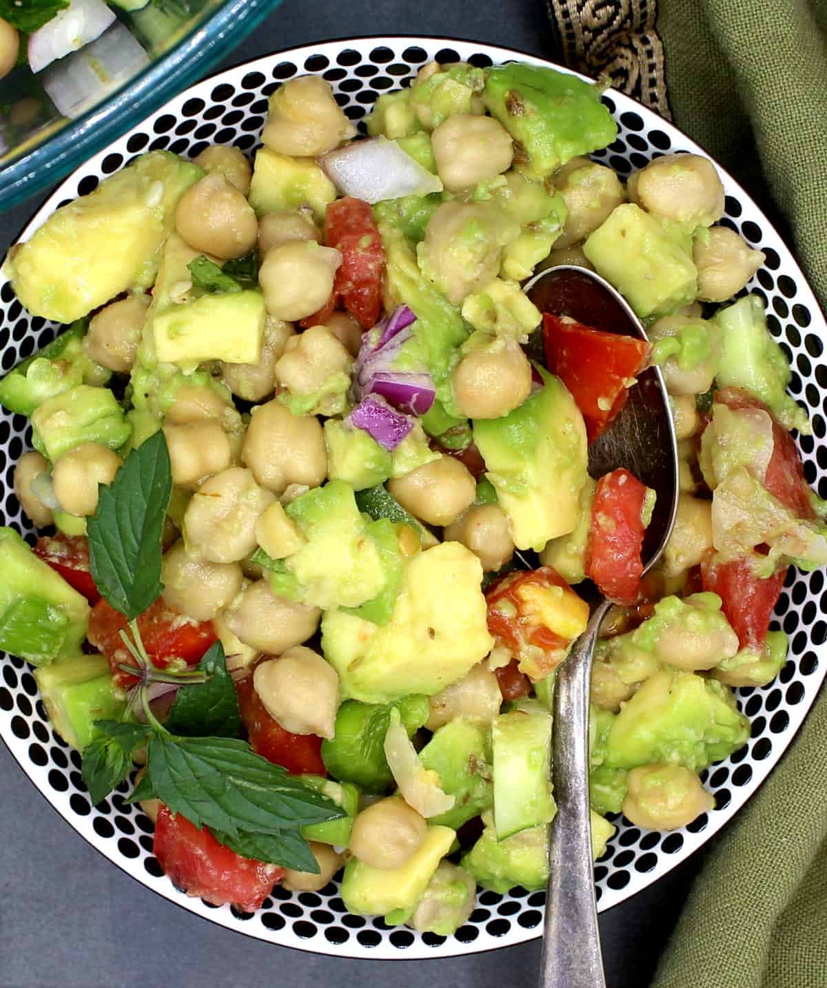 Bowl of chickpea avocado salad with a sprig of mint.