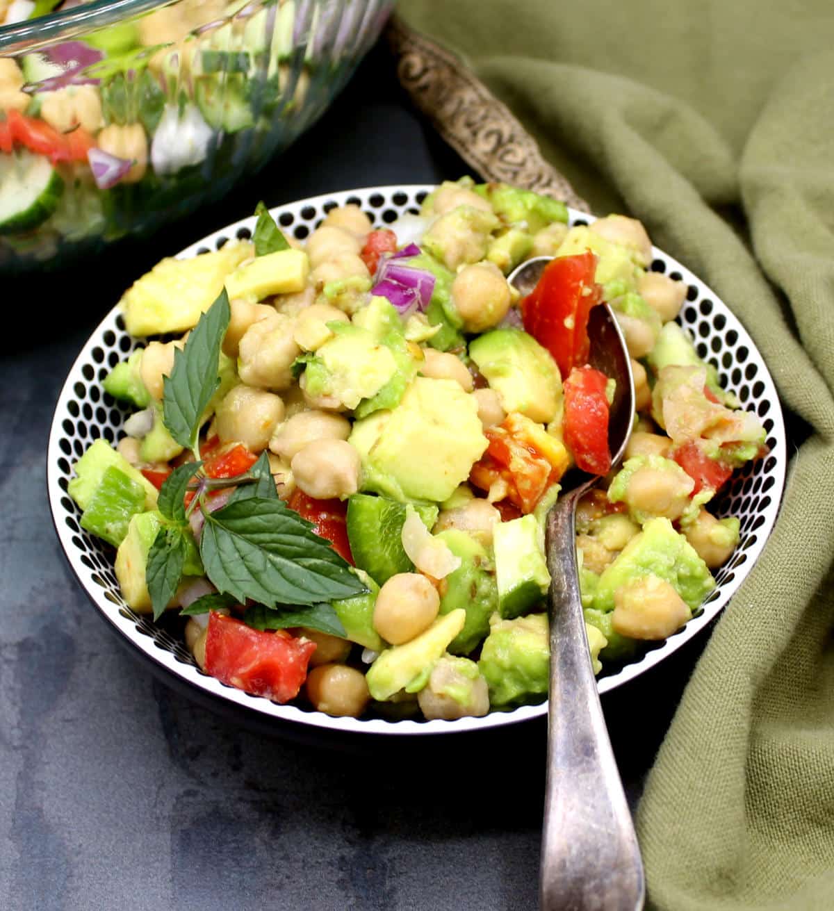 A bowl of chickpea avocado salad with spoon.